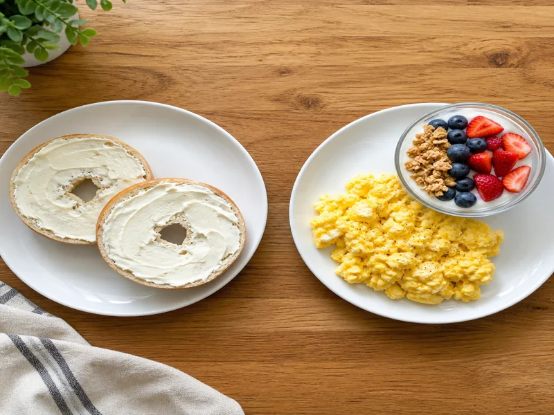 Side-by-side breakfast comparison: bagel on one plate, eggs and yogurt on the other