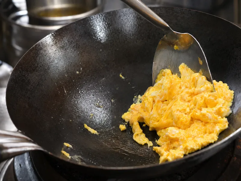 Sbattere le uova nel wok caldo e spingerle di lato