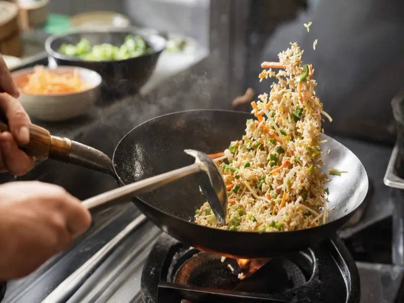 Saltare il riso freddo con le verdure nel wok a fuoco alto con leggera crosticina
